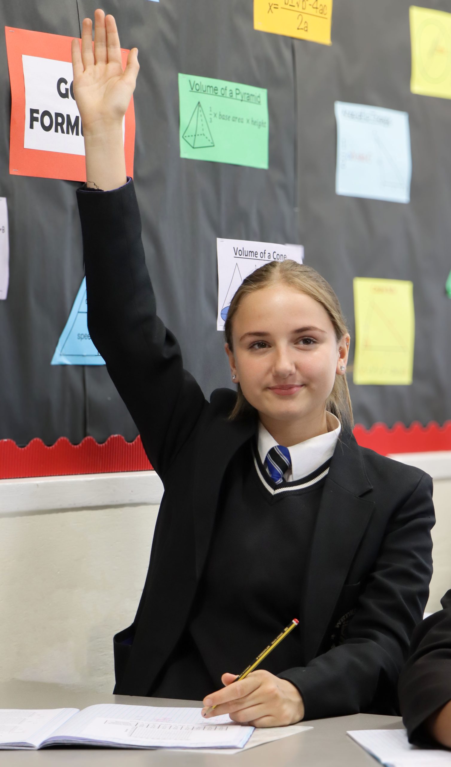 Girl in a classroom with her hand up